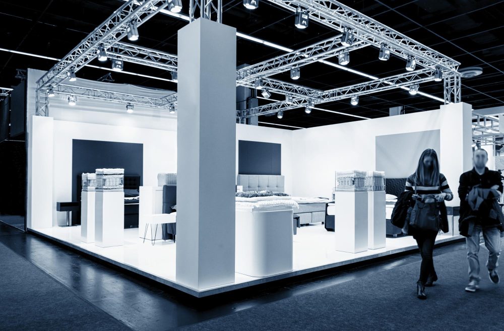 Expo booth design Empty white exhibition booth under an overhead lighting truss at a trade show