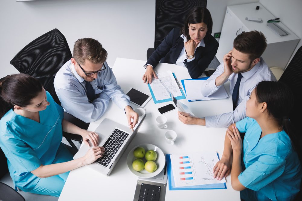 Healthcare and business professionals discussing a project around a meeting table